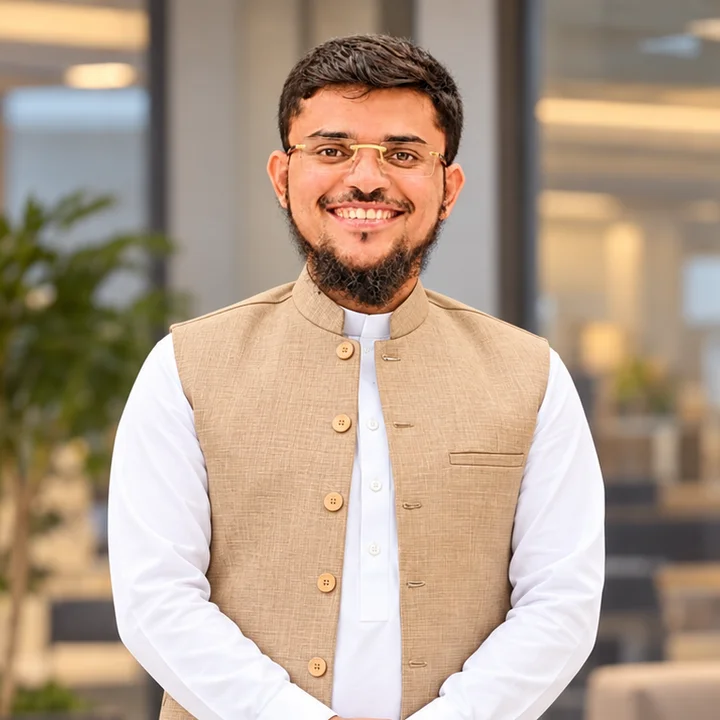 Portrait of Inam Ur Rehman, smiling, in a white kurta and a beige waistcoat