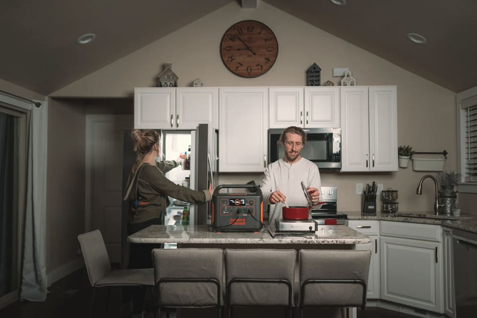Two people in a home kitchen with a portable power station on the counter