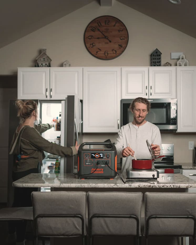 Two people in a home kitchen with a portable power station on the counter